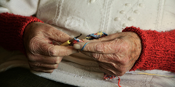 An older woman crocheting, focused on her hands