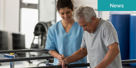 Physiotherapist helping a senior patient while he walks using his hands to support his weight on the bars