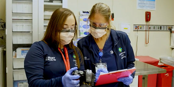 Two forensic nurse examiners take notes based on pictures on a digital camera.