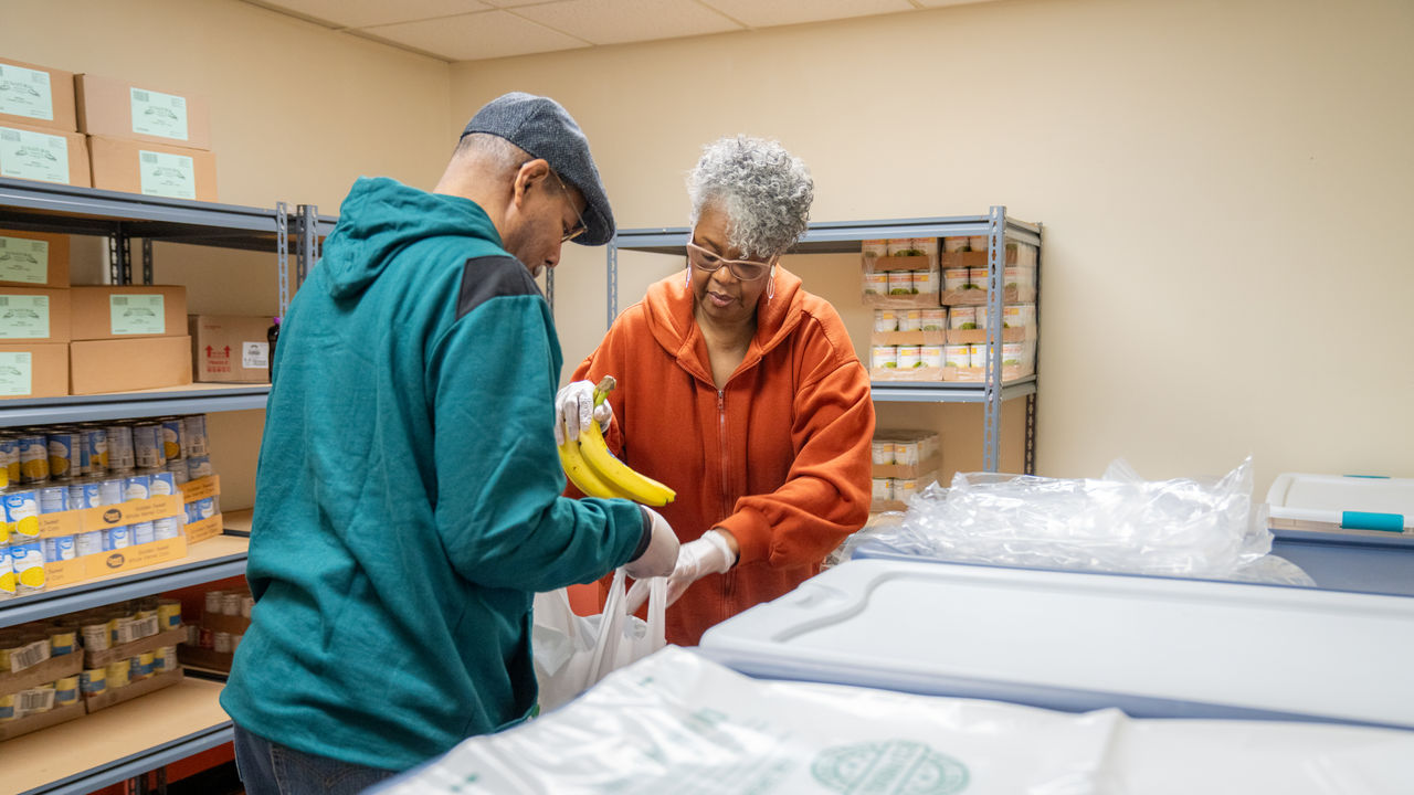 Two community health workers bag groceries to be given to the community Two community health workers bag groceries to be given to the community
